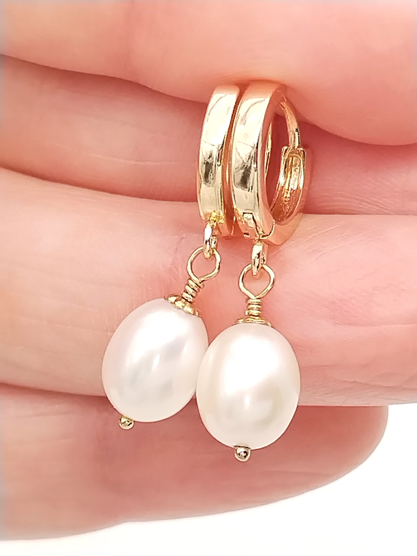 Pequeños aretes de aro dorados con delicada perla colgante