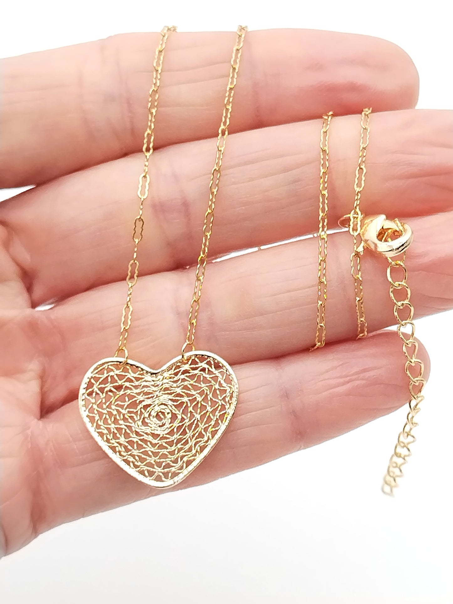 Close-up of gold heart pendant on delicate chain necklace