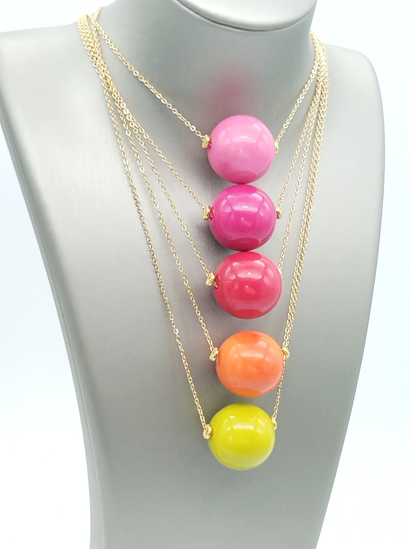 Orange tagua bead pendant on gold chain necklace against white background