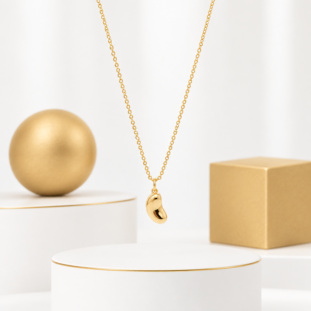 Polished bean charm suspended from a delicate gold plated link chain