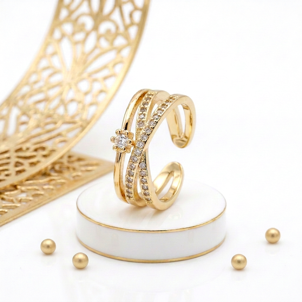 18k Gold Plated adjustable crossover ring standing upright among small geometric gold props