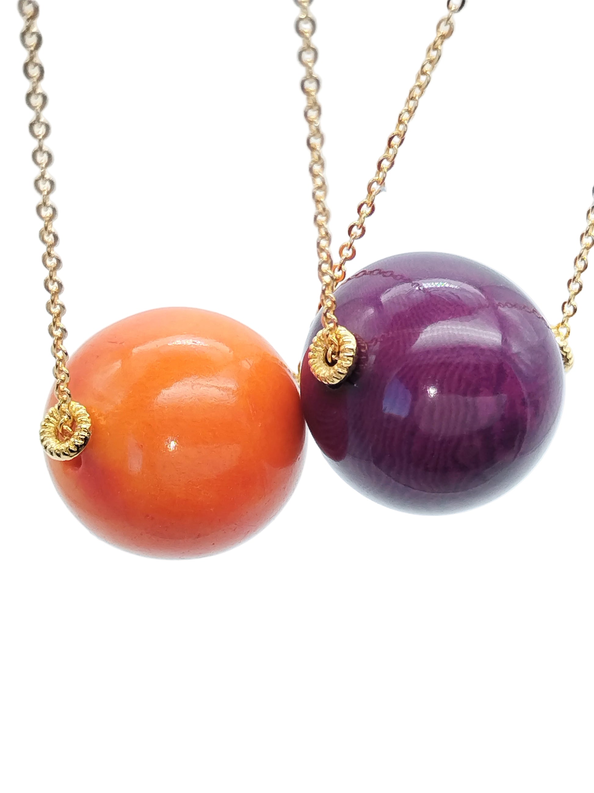 Orange tagua bead pendant on gold chain necklace against white background