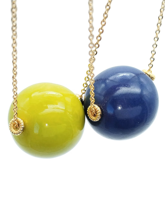 Pistachio green tagua bead pendant on gold chain necklace against white background