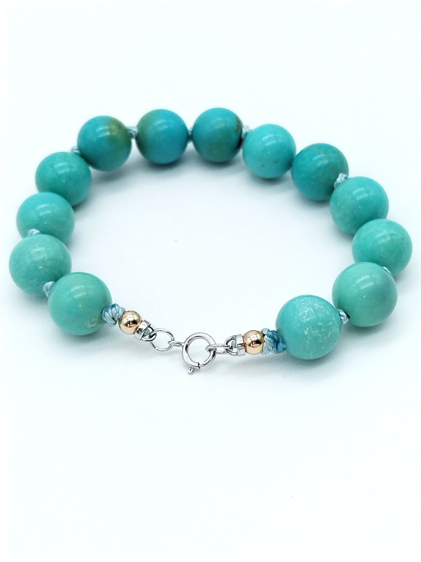 Side view of turquoise beaded bracelet displaying bead arrangement and gold knot detail