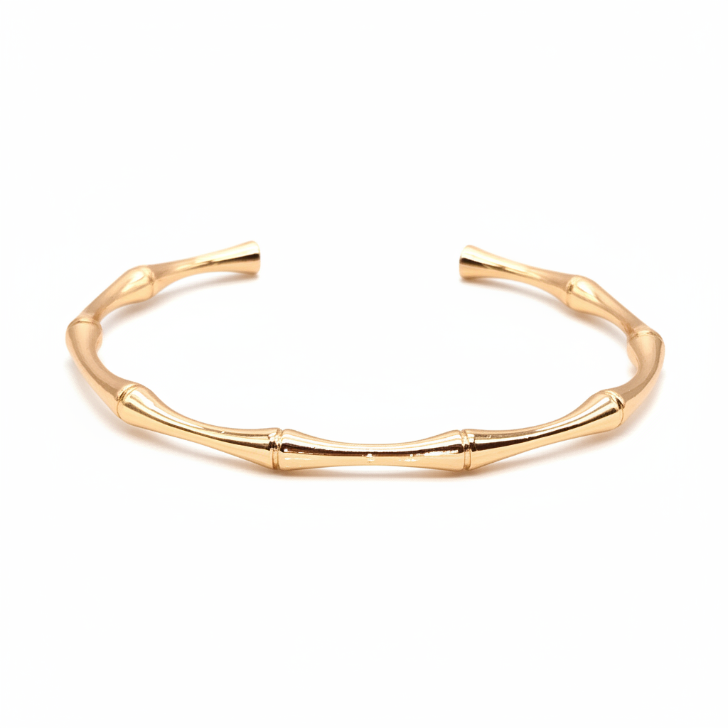 18k gold bamboo cuff bracelet displayed on white and gold surface with natural lighting