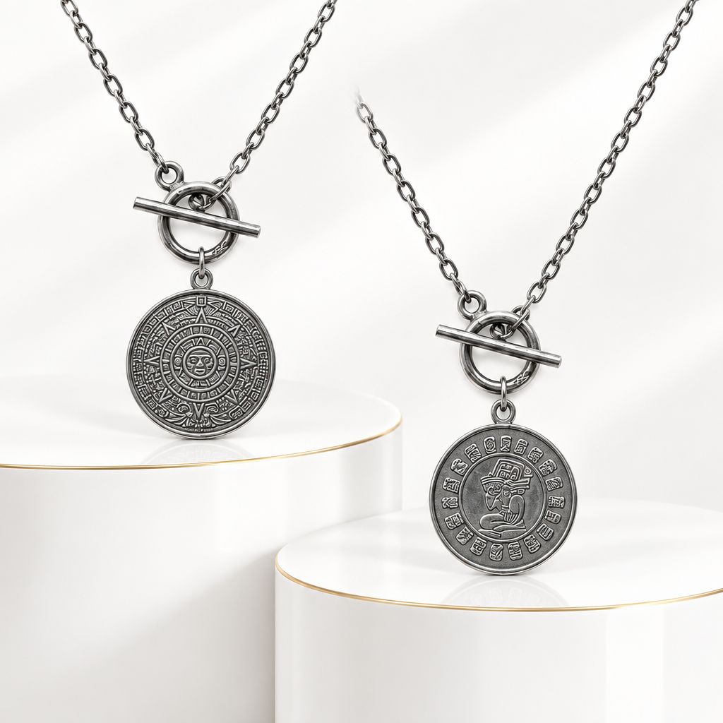 Both engraved sides of a reversible sterling silver coin necklace displayed on white podiums