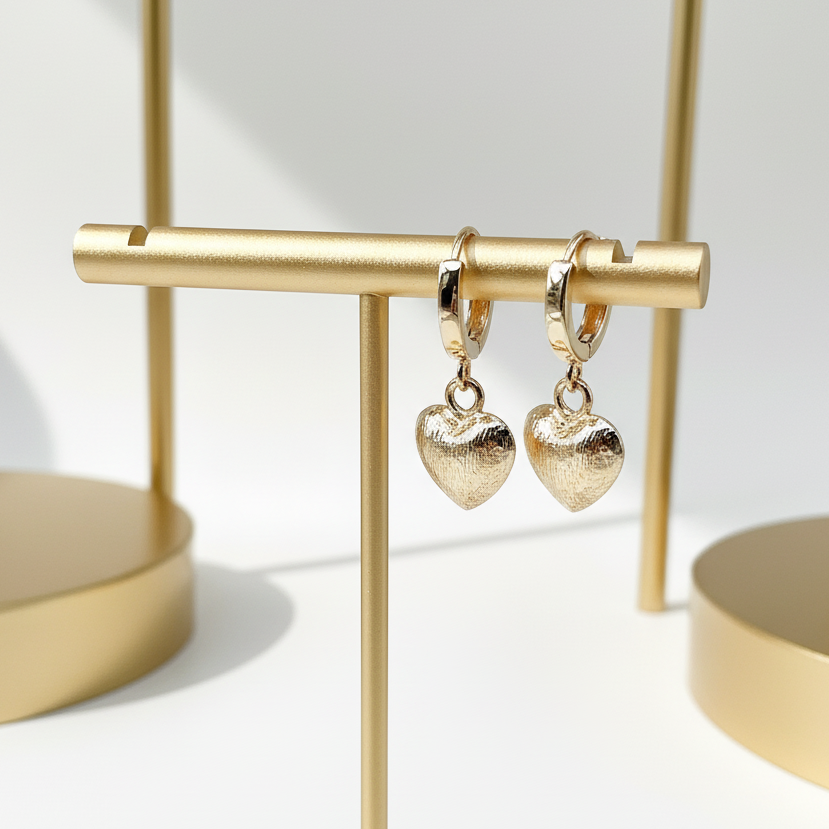 Gold heart huggie hoop earrings displayed on jewelry stand