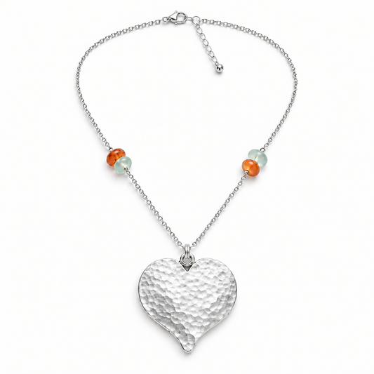 Long sterling silver necklace with a large hammered silver-plated heart and green and caramel chalcedony rondelles on a white background