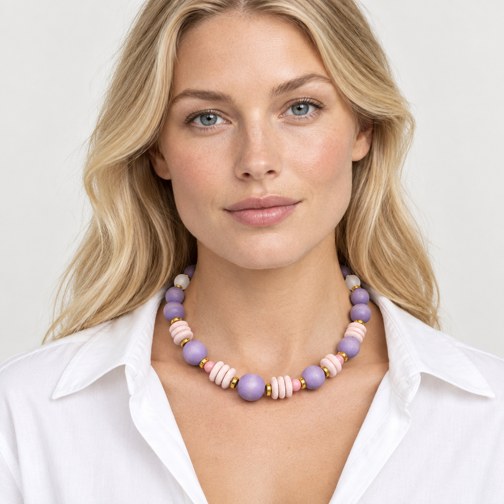 Model wearing a lavender and blush pink beaded choker with gold-tone accents and an open-collar white shirt