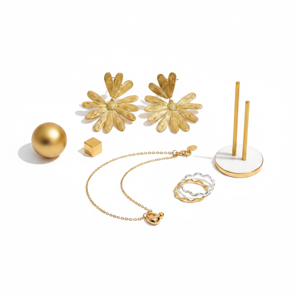 Gold jewelry set flat lay with flower stud earrings, charm and bead necklace and wave band ring
