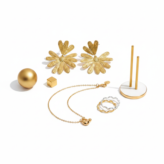 Gold jewelry set flat lay with flower stud earrings, charm and bead necklace and wave band ring
