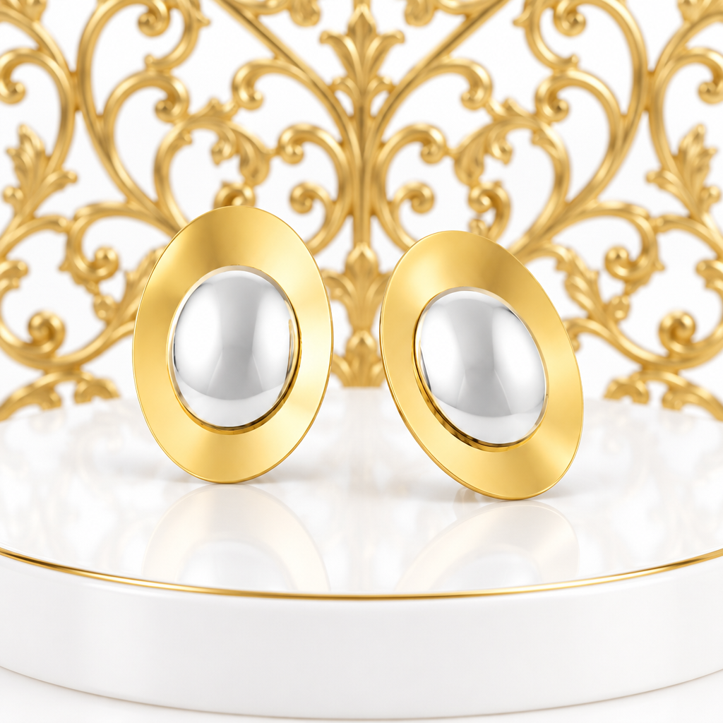 Two tone oval stud earrings on a glossy white podium with an ornate gold filigree grille directly behind
