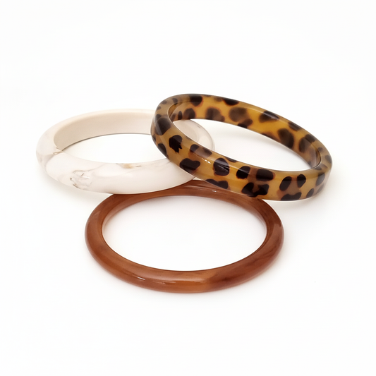 Set of 3 resin bangles in animal print, beige and caramel stacked together on white background