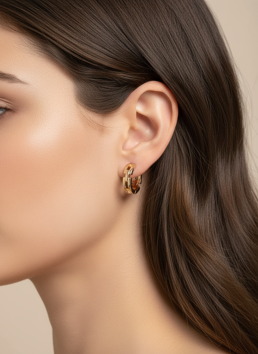 Small gold huggie earrings on brown-haired model