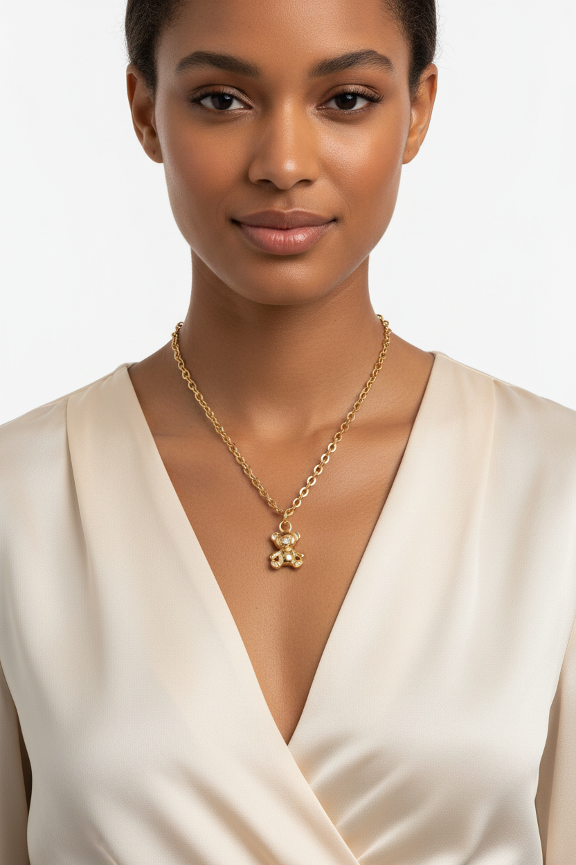 Woman wearing 18k gold plated teddy bear charm necklace with CZ detail on gold filled chain, elegant V-neck blouse
